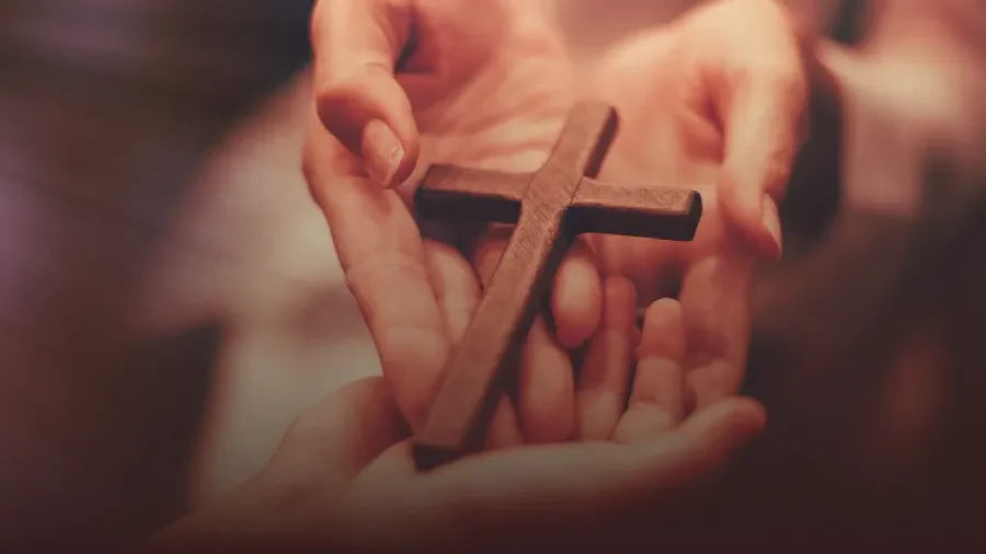 Healing Hands giving a cross to another person, symbolizing Salvation through Jesus Christ